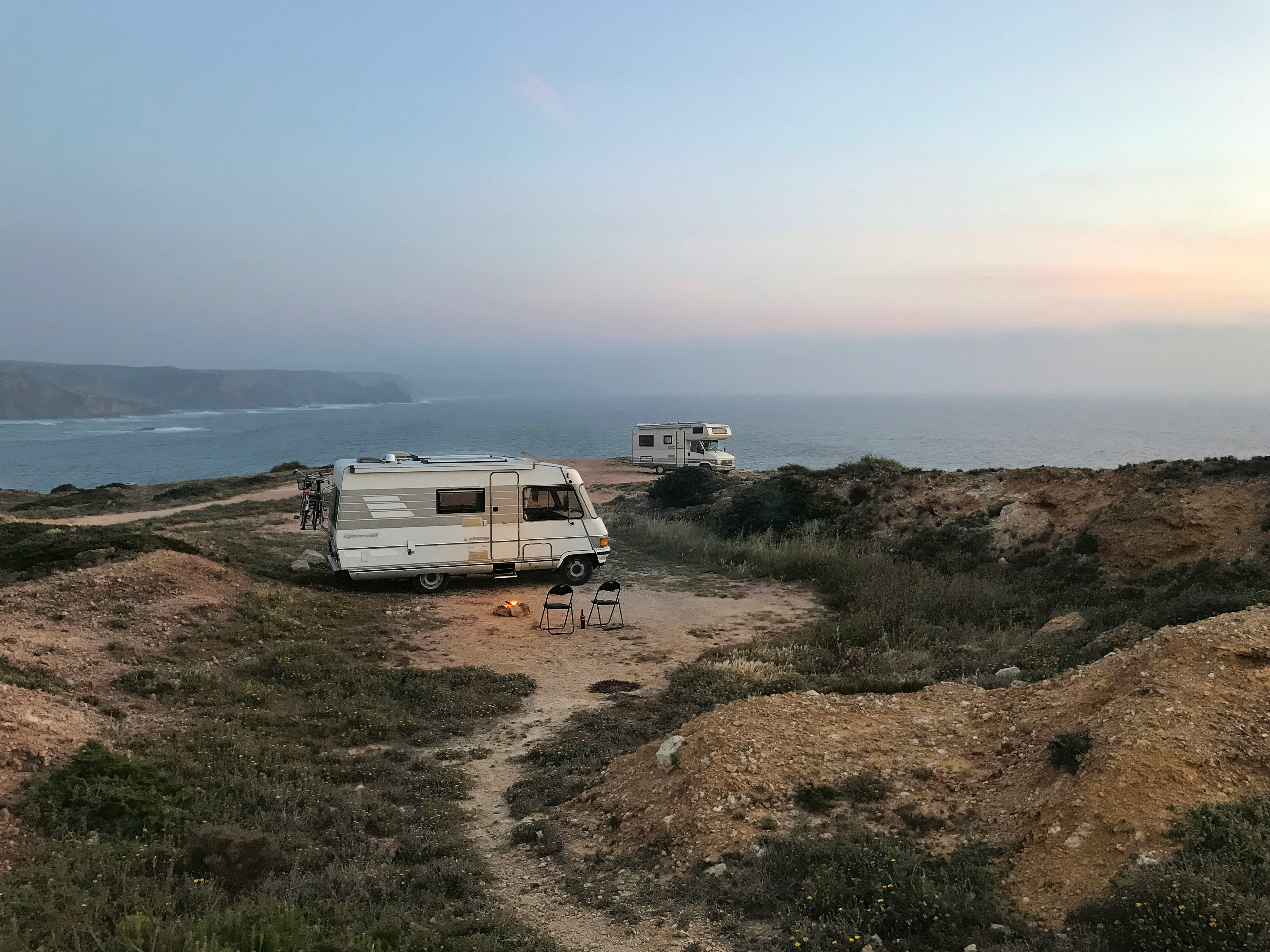 Campervans parked at a cliff edge at sunset, Portugal